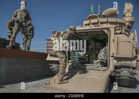 Soldaten beginnen, ein Bradley-Kampffahrzeug mit Munitionsmaterial zu laden, um sich auf den Qualifikationskurs für Waffen vorzubereiten. Charlie Company aus dem 116. Kampfteam der Kavalleriebrigade begann am 1. Mai 2021 das jährliche Training und kehrte am 13. Mai aus dem Orchard Combat Training Center zurück. Die Männer und Frauen von C Company absolvierten eine erfolgreiche und herausfordernde jährliche Schulung im OCTC, bei der Bradley Gunnery Table VI absolviert und 11 Bradley-Crews qualifiziert wurden. Die abtaufenden Infanterieeinheiten absolvierten ihre Qualifikation für alle sechs Kader. Die Trainingsübungen im Feld beinhalteten die Situation Stockfoto