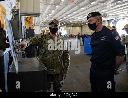 Adm. Tony Radakin, britischer Royal Navy First Sea Lord und Chief of the Naval Staff, erhält einen Brief vom Mate 1st Class James Keetthe von Machinist über das Plasma-Arc-Abfallzerstörungssystem der USS Gerald R. Ford (CVN 78) in der Hangar Bay des Schiffes, 6. Mai 2021. Der erste Sea Lord und eine britische Delegation verbrachten zwei Tage in Hampton Roads im Rahmen der Besuchsreihe zwischen den USA und Großbritannien, wo sie sich mit der Führung der US-Navy-Flotte traf, um über die Stärkung unserer kollektiven Bemühungen um die Sicherheit im Seeverkehr in dieser Ära des großen Machtwettbewerbs zu diskutieren. Stockfoto