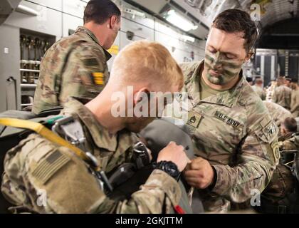 Ein Jumpmaster der 82. Airborne Division hängt Kampfausrüstung an einem Fallschirmjäger, der dem Kampfteam der 3. Brigade, 82. ABN, zugewiesen ist. Div. An Bord eines C-17 Globemaster III, der während der Übung Swift Response 21 nach Estland gebunden wurde, 7. Mai 2021. Swift Response 21 ist eine gemeinsame, multinationale Flugübung, an der mehr als 7,000 Fallschirmjäger aus 10 NATO-Staaten beteiligt sind. Stockfoto