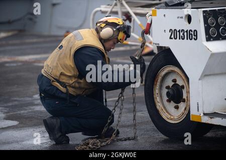 210506-N-FO865-1024 GOLF VON ALASKA (6. Mai 2021) – der US Navy Aviation Boatswain's Mate (Handling) 2nd Class Richard Sarmiento sichert sich einen Schlepper auf dem Flugdeck an Bord des Amphibientransportschiffes USS San Diego (LPD 22). Die Makin Island Amphibious Ready Group und die 15. Marine Expeditionary Unit führen derzeit Routineoperationen im Einsatzgebiet der 3. US-Flotte durch. Stockfoto