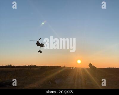 NURMSI, Estland – Ein CH-47 Chinook mit Ausrüstung im Schlepptau hebt ab, als Soldaten der 3. Brigade, 82. Airborne Infantry Division am 8. Mai 2021 in Nurmsi, Estland, warm bleiben. Diese Luftangriffsübung ist Teil von Swift Response 21, einer verbundenen Übung von DEFENDER-Europe 21. DEFENDER-Europe 21 ist eine groß angelegte Übung unter Führung der US-Armee, die darauf ausgelegt ist, Bereitschaft und Interoperabilität zwischen den USA, NATO-Verbündeten und Partnermilitärs aufzubauen. In diesem Jahr werden mehr als 28,000 multinationale Streitkräfte aus 26 Nationen nahezu simultan Operationen in mehr als 30 Trainingsbereichen in mehr als einem Dutzend Ländern durchführen Stockfoto