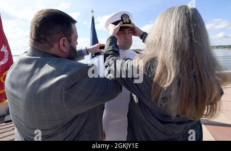 MADISON, Wis. (8. Mai 2021) während einer Inbetriebnahmezeremonie auf dem Monona Terrace Community and Convention Center, 8. Mai, hat der US-Navy-Ensign Garrett Latchaw seine Offiziersabdeckung von seinen Eltern Scott und Kristine Latchaw aufgesetzt. Latchaw war Mitglied des Naval Reserve Officers Training Corps (NROTC) der University of Wisconsin-Madison. Das NROTC-Programm wird vom Naval Service Training Command überwacht und wurde eingerichtet, um Midshipmen geistig, moralisch und physisch zu entwickeln, um die höchsten Verantwortlichkeiten in Bezug auf Kommando, Staatsbürgerschaft und Regierung zu übernehmen. Stockfoto