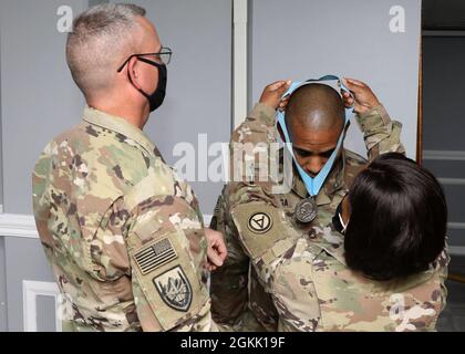 Army Support Center-Kuwait Headquarters and Headquarters Company 1st Sgt. Kimberly Goode präsentiert Staff Sgt. Kenji Motonaga, ein Kampfmediziner und nicht beauftragter Offizier des Lagers Arifjan, Kuwait, Truppenmedizinische Klinik, mit der Sgt. Audie Murphy Club Medaillon bei der Einweihungszeremonie am 10. Mai 2021 in Motonaga, zusammen mit Command Sgt. Maj. Keith A. Gwin, der Senior-Berater des stellvertretenden Generalkommandanten des 1. Theater Sustainment Command. Goode, der Motonaga für die 1. TSC-ASG-Kuwait SAMC, das Camp-Kapitel der Elite-NCO-Organisation, gesponsert hat. Stockfoto