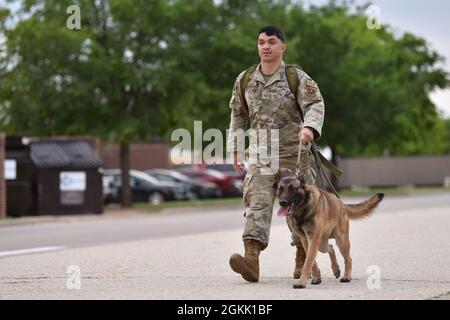 US Air Force Staff Sgt. Nichola Suitonu, 17. Sicherheitskräfte-Squadron, militärischer Hundeführer, geht mit Zekk, 17. SFS MWD, während eines Rucks um den Goodfellow Air Force Base, Texas, 10. Mai 2021. Der Ruck war das erste von mehreren Veranstaltungen, die während der National Police Week stattfanden. Stockfoto