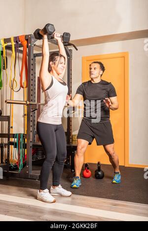 Frau macht Schultertraining mit Hanteln im Fitnessstudio Stockfoto