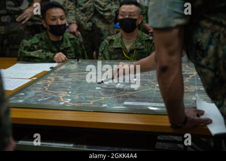 Capt. Christopher Ramos, ein Verbindungsoffizier mit der III Marine Expeditionary Force, informiert die Anführer und Truppen jeder Truppe über die bevorstehenden Entwicklungen für die Übung Jeanne D’Arc 21, Camp Ainoura, Sasebo, Japan, 12. Mai, 2021. Während der Mitarbeiterübung teilen sich die Führungskräfte jeder Kraft die Planungsverfahren zur Vorbereitung auf die Durchführung von Feldschulungen. ARC-21 bietet den US-amerikanischen, französischen, japanischen und australischen Streitkräften die Möglichkeit, Erfahrungen, Taktiken und Best Practices auszutauschen, um ihre Fähigkeiten gemeinsam zu verbessern. Stockfoto