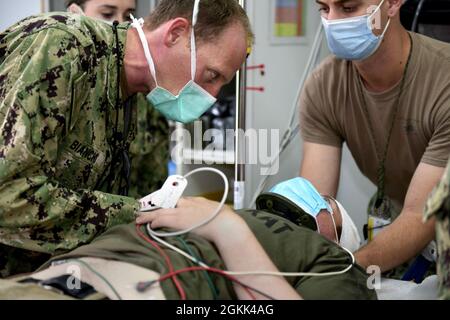 CAMP LEMONNIER, Dschibuti (12. Mai 2021) U.S. Navy LT. Cmdr. Will Bianchi, ein Arzt für Notfallmedizin aus San Diego, evaluiert die simulierte Kopfverletzung von SPC der US-Armee. Aaron Wood, von Norwalk Conn., während einer Basisübung im Camp Lemonnier, 12. Mai 2021. In der Schulung wurden Kenntnisse und Kenntnisse zur ordnungsgemäßen Evakuierung und Behandlung von Patienten während eines Massenereignisses getestet. Stockfoto