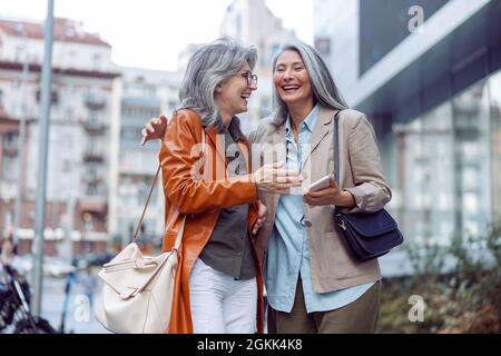 Schöne grauhaarige Frauen Gefährten auf der modernen Stadtstraße zu Fuß Stockfoto
