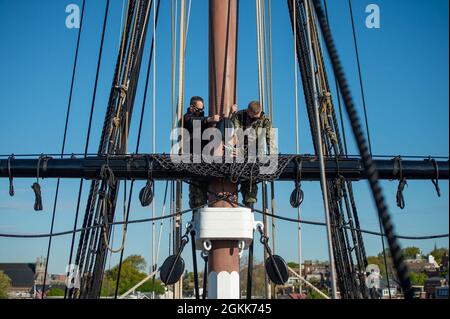 BOSTON (13. Mai 2021) Master-at-Arms First Class Travis Hagerty, links, aus Gilbert, Arizona, und Culinary Specialist 2nd Class Blake Bentz, aus Ludington, Michigan, besteigen den Mizzen Top Yard an Bord der USS Constitution. USS Constitution, das älteste in Auftrag gegebene Kriegsschiff der Welt, spielte eine entscheidende Rolle in den Barbarenkriegen und dem Krieg von 1812 und verteidigte von 1797 bis 1855 aktiv die Seewege. Während des normalen Betriebs bieten die an Bord der USS Constitution stationierten aktiven Seeleute kostenlose Touren an und bieten mehr als 600,000 Menschen pro Jahr öffentliche Besuche an, da sie die Mission des Schiffes unterstützen Stockfoto