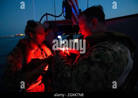 GOLF VON TADJOURA (13. Mai 2021) US-Küstenwache LT. Cmdr. Benjamin Lehrfeld, Kommandant der Task Group 68.6, Und Botswain Mate 2nd Class Jonghyun Lee aus Buenos Aires, Argentinien, bringt Nachtsichtgeräte an ihre Helme an, um nicht identifizierte Schiffe besser erkennen zu können, während sie die Charles Molthrope, Coast Guard Patrol Craft (WPC 1141) und Robert Goldman (WPC 1142), Cutter der Küstenwache der Sentinel-Klasse, beobachten Stockfoto