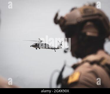 OKINAWA, Japan – Ein Green Beret der US-Armee mit 1. Bataillon, 1. Spezialeinheit (Airborne) kommuniziert mit einem Sikorsky HH-60-Hubschrauber der US-Marine und dem Hubschrauber Sea Combat Squadron 85 während des Nahkampftrainings am 13. Mai 2021. Green Berets trainierten mit dem Call for Fire mit 5 Leitungen und lenkten das Flugzeug zu Zielen, um Elemente der Bodentruppe zu unterstützen. Stockfoto