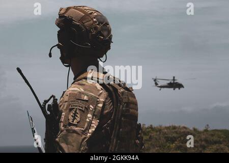 OKINAWA, Japan – Ein Green Beret der US-Armee, der dem 1. Bataillon, der 1. Special Forces Group (Airborne), zugewiesen wurde, kommuniziert mit einem Sikorsky HH-60-Hubschrauber der US-Marine und dem Sea Combat Squadron 85 des Hubschraubers während des Nahkampftrainings am 13. Mai 2021. Green Berets trainierten mit dem Call for Fire mit 5 Leitungen und lenkten das Flugzeug zu Zielen, um Elemente der Bodentruppe zu unterstützen. Stockfoto