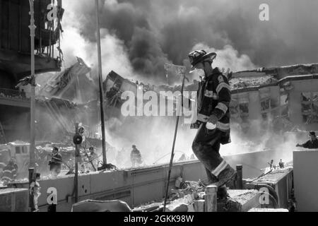 FDNY-Feuerwehrmann unter den Trümmern, während die Twin Towers während des Terroranschlags in New York City am 11. September 2001 brennen. (USA) Stockfoto