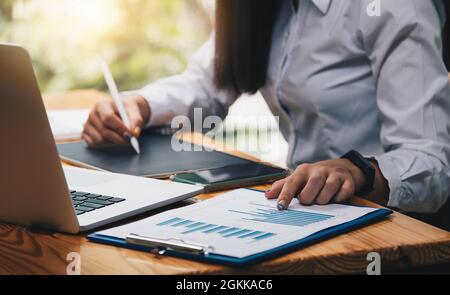Geschäftsfrau, die mit Finanzen über Kosten und Rechner und Tablet arbeitet, mit Stift in ihrem Büro Stockfoto