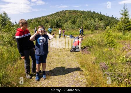 Baiersbronn, Deutschland. August 2021. Zwei Junior Rangers spielen während einer Wanderpause ein Spiel, wobei einer mit verbundenen Augen durch die Natur geht. Kinder im Alter von fünf bis zwölf Jahren können Junior Rangers im Nationalpark sein. In kleinen Gruppen lernen sie grundlegende Fakten über Natur und Tiere, später lernen sie unter anderem über die Kologie, warum der Nationalpark existiert und wie sie sich mit Karte und Kompass orientieren können. Quelle: Philipp von Ditfurth/dpa/Alamy Live News Stockfoto