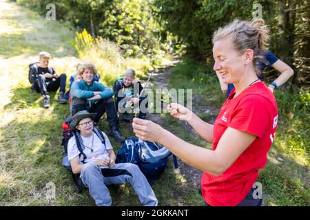 Baiersbronn, Deutschland. August 2021. Erzieherin Svenja Fox (r) erklärt den Junior Rangers den Unterschied zwischen Blaubeeren und Preiselbeeren. Kinder im Alter von fünf bis zwölf Jahren können Junior Rangers im Nationalpark sein. In kleinen Gruppen lernen sie die Grundlagen über Natur und Tiere, später lernen sie über die Kologie, warum der Nationalpark existiert und wie man sich mit Karte und Kompass orientiert. Quelle: Philipp von Ditfurth/dpa/Alamy Live News Stockfoto