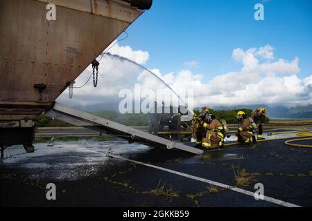 Feuerwehrleute des 142. Flügels der Oregon Air National Guard führen eine Live-Feuerübung mit Marine Corps-Feuerwehrleuten auf der Marine Corps Base, Hawaii, 14. Mai 2021 durch. Dieser Brand ist Teil einer größeren gemeinsamen Übung, die das Einlernen von Flugzeugen, Ausstiegsschulungen sowie die gemeinsame Schulung und Betreuung weniger erfahrener Feuerwehrleute umfasst. Stockfoto