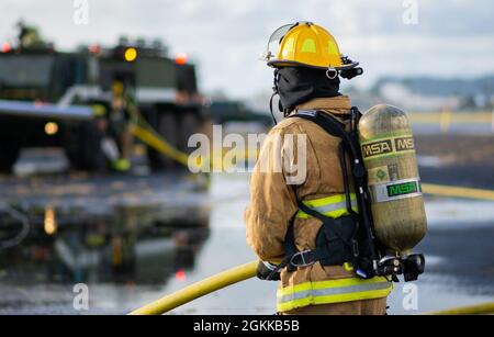 Ein Feuerwehrmann des 142. Flügels der Oregon Air National Guard nimmt an einer Live-Feuerübung mit Marine Corps-Feuerwehrleuten auf der Marine Corps Base, Hawaii, 14. Mai 2021 Teil. Dieser Brand ist Teil einer größeren gemeinsamen Übung, die das Einlernen von Flugzeugen, Ausstiegsschulungen sowie die gemeinsame Schulung und Betreuung weniger erfahrener Feuerwehrleute umfasst. Stockfoto