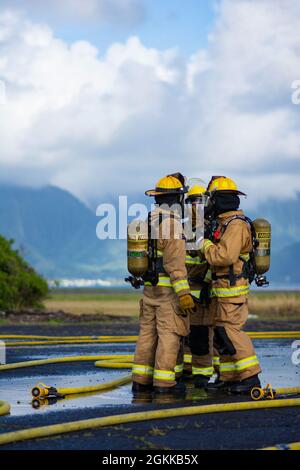 Feuerwehrleute des 142. Flügels der Oregon Air National Guard führen eine Live-Feuerübung mit Marine Corps-Feuerwehrleuten auf der Marine Corps Base, Hawaii, 14. Mai 2021 durch. Dieser Brand ist Teil einer größeren gemeinsamen Übung, die das Einlernen von Flugzeugen, Ausstiegsschulungen sowie die gemeinsame Schulung und Betreuung weniger erfahrener Feuerwehrleute umfasst. Stockfoto