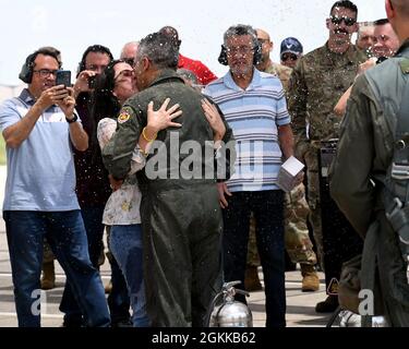 Col. Raul Rosario, Kommandant des 149. Kampfflügels, küsst seine Frau, nachdem er von seinem letzten Flug in einem F-16 Fighting Falcon auf der Joint Base San Antonio-Lackland, Texas, am 14. Mai 2021 zurückgekehrt ist. Der „fini-Flug“ ist eine langjährige Tradition der Luftwaffe, die als Meilenstein für die Karriere von Piloten, die sich dem Ruhestand nähern, dient. Freunde, Familie und Mitarbeiter geben dem Piloten traditionell Wasser und/oder eine Flasche Champagner beim letzten Ausstieg aus dem Flugzeug. (Fotos der Air National Guard von Mindy Bloem) Stockfoto