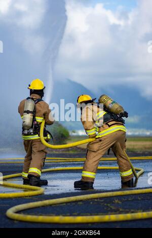 Feuerwehrleute des 142. Flügels der Oregon Air National Guard führen eine Live-Feuerübung mit Marine Corps-Feuerwehrleuten auf der Marine Corps Base, Hawaii, 14. Mai 2021 durch. Dieser Brand ist Teil einer größeren gemeinsamen Übung, die das Einlernen von Flugzeugen, Ausstiegsschulungen sowie die gemeinsame Schulung und Betreuung weniger erfahrener Feuerwehrleute umfasst. Stockfoto