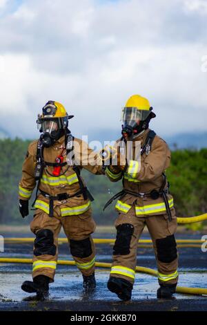 Feuerwehrleute des 142. Flügels der Oregon Air National Guard führen eine Live-Feuerübung mit Marine Corps-Feuerwehrleuten auf der Marine Corps Base, Hawaii, 14. Mai 2021 durch. Dieser Brand ist Teil einer größeren gemeinsamen Übung, die das Einlernen von Flugzeugen, Ausstiegsschulungen sowie die gemeinsame Schulung und Betreuung weniger erfahrener Feuerwehrleute umfasst. Stockfoto