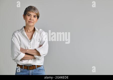 Attraktive asiatische Frau mittleren Alters mit gefalteten Armen isoliert auf weißem Hintergrund Stockfoto
