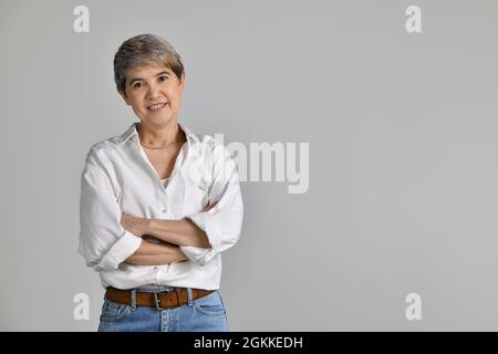 Attraktive asiatische Frau mittleren Alters mit gefalteten Armen isoliert auf weißem Hintergrund Stockfoto