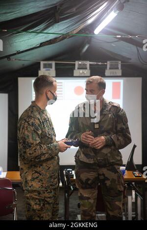 Oberstleutnant Jeremy Nelson, Kommandeur der Seestreitkräfte (links) und Oberstleutnant Henry Marcaillou, Kommandant der französischen Bodentruppen für die Übung, tauschen Geschenke aus, die die Fertigstellung der Jeanne D’Arc 21 im Kirishima Manövergebiet, Japan, am 16. Mai 2021 fortsetzen. Die Lehren und Praktiken, die wir mit unseren japanischen, französischen und australischen Verbündeten während der ARC-21 teilen, machen uns alle besser in der Lage, auf Krisen im gesamten Indo-Pazifik zu reagieren, sei es bei der Verteidigung Japans, der Reaktion auf Notfälle in anderen Teilen der Region oder auch wenn wir zu humanitären Hilfsmaßnahmen oder Katastrophenhilfe aufgerufen werden. Stockfoto