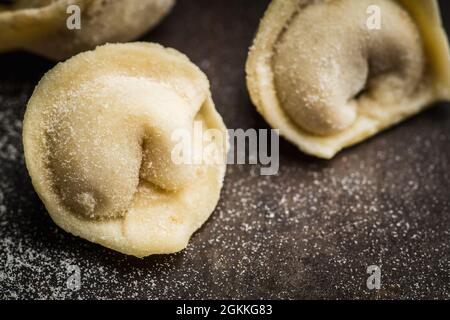 Rohe Knödel in Mehl auf dem Tisch. Russische nationale Küche. Selektiver Fokus. Stockfoto