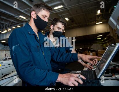 210517-N-IG124-1028 ATLANTISCHER OZEAN (17. Mai 2021) Flugzeugtechniker 2. Klasse Maxim Burroughs, links, von Colorado Springs, Colorado, Und der Flugzeugtechniker Airman Ethan Reed, rechts, aus Battle Creek, Michigan, führt während der Probefahrt nach einer erweiterten Verfügbarkeit der Fluggesellschaft eine Fehlersuche an einem Spotting Dolly-Elektrosystem in der Hangarbucht des Nimitz-Klasse-Flugzeugträgers USS Harry S. Truman (CVN 75) durch. Zu den Probefahrten gehört ein umfassender Test der Systeme und Technologien des Schiffes, um sicherzustellen, dass das Schiff bereit ist, den Betrieb wieder aufzunehmen Stockfoto