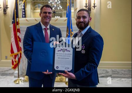 Kevin J. Stitt, Gouverneur von Oklahoma, posiert mit Aurash Zarkashan, dem Beamten des Polizeidezernats von Tulsa, nachdem er Zarkashan während einer Zeremonie im Oklahoma State Capitol in Oklahoma City am 18. Mai 2021 eine Oklahoma Purple Heart Medal überreicht hatte. Stockfoto