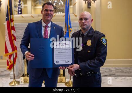 Kevin J. Stitt, Gouverneur von Oklahoma, posiert mit dem Polizeibeamten Zachary Barby von Oklahoma City, nachdem er ihm am 18. Mai 2021 im Oklahoma State Capitol in Oklahoma City die Oklahoma Purple Heart Medal überreicht hatte. Stockfoto