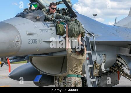 John Hamilton, Major der US-Luftwaffe, 555. Jagdgeschwader F-16 Fighting Falcon Pilot, übergibt nach der Teilnahme an Astral Knight 2021 (AK21) auf der Aviano Air Base, Italien, am 18. Mai 2021, einen Ausrüstungstaschen an Senior Airman Juan Monroy, den Leiter der 555. F-16 Aircraft Maintenance Unit. AK21 ist eine von den US-Luftstreitkräften in Afrika geführte Übung, bei der Luftwaffe, Soldaten und Matrosen aus den USA mit Mitgliedern aus Albanien, Kroatien, Griechenland, Italien und Slowenien zusammenarbeiten. AK21 ist eine integrierte Luft- und Raketenabwehrübung, die sich auf die Verteidigung von Schlüsselgeländen konzentriert. Stockfoto