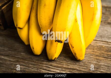 Zweig der Bananen auf dem rustikalen Hintergrund. Selektiver Fokus. Geringe Schärfentiefe. Stockfoto