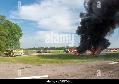 Feuerwehrleute, die dem 180. Kampfflügel der Ohio National Guard zugewiesen wurden, reagieren zusammen mit mehreren örtlichen Feuerwehren auf einen kontrollierten Brand während eines simulierten Flugzeugverhagens auf dem Eugene F. Kranz Toledo Express Airport in Swanton, Ohio, 18. Mai 2021. Die Übung gab lokalen militärischen und zivilen Ersthelfern die Möglichkeit, gemeinsam an hochwertigen praktischen Erfahrungen in einem gemeinsamen Umfeld zu arbeiten und sicherzustellen, dass sie für den Fall eines realen Flugzeugversages bereit sind. Stockfoto