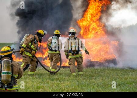 Feuerwehrmänner, die dem 180. Kampfflügel der Ohio National Guard zugewiesen wurden, sowie mehrere örtliche Feuerwehren, löschten am Eugene F. Kranz Toledo Express Airport in Swanton, Ohio, am 18. Mai 2021 einen kontrollierten Brand aus. Die Übung gab lokalen militärischen und zivilen Ersthelfern die Möglichkeit, gemeinsam an hochwertigen praktischen Erfahrungen in einem gemeinsamen Umfeld zu arbeiten und sicherzustellen, dass sie für den Fall eines realen Flugzeugversages bereit sind. Stockfoto