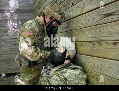 FORT DRUM, N.Y. – CPL der US-Armee. Dakoatah Miller, ein Infanterist des 2. Bataillons der New Yorker Nationalgarde, 108. Infanterie-Regiment, behandelt während der 10. Mountain Division Expert Infantryman Badge Assessment in Fort Drum, N.Y., 19. Mai 2021 eine simulierte Kopfwunde unter chemischen, biologischen, radiologischen und nuklearen (CBRN) Bedingungen. Bei den Tests der EIB handelt es sich um eine fünftägige Bewertung, die sich auf die Landschifffahrt, die Waffenqualifikation, einen 12-Meilen-marsch und mehrere Einzelaufgaben zur Prüfung der Infanteriefähigkeiten konzentriert. Stockfoto