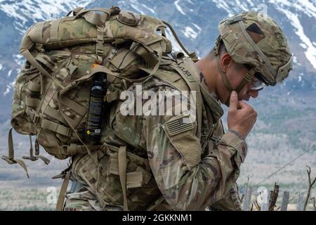 SPC Castulo Molina, 4th Infantry Brigade Combat Team (Airborne), 25th Infantry Division, ruft während des US Army Alaska Best Warrior Competition, 19. Mai 2021 im Northern Warfare Training Center der US Army, Black Rapids Training Site, Alaska, in einem simulierten SPOT-Bericht auf. Stockfoto