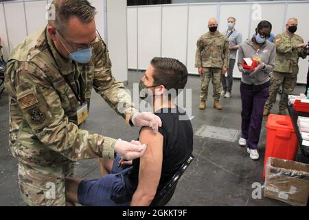 Tom Pescatore, 26, aus Manhattan, NY, erhält am 20. Mai 2021 seine zweite Pfizer-Impfung von der New York Air National Guard, LTC John Reynolds, einer registrierten Krankenschwester, 105. Luftaufzugsflügel, mit Dateneingabe durch die Technikerin Melissa Chucaralao. Dies markiert den 600,000-Impfstoff, der an der Massenimpfstelle des Jacob Javits Center verabreicht wurde. Am 13. Januar 2021 begannen die Impfbemühungen des New Yorker Gesundheitsministeriums für die Einwohner von New York am Impfort Javits. Mehr als 3,180 Mitglieder der New Yorker Armee- und Luftnationalgarde, der New Yorker Naval Miliz und der New Yorker Garde unterstützen t Stockfoto