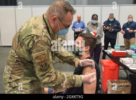 Tom Pescatore, 26, aus Manhattan, NY, erhält am 20. Mai 2021 seine zweite Pfizer-Impfung von der New York Air National Guard, LTC John Reynolds, einer registrierten Krankenschwester, 105. Luftaufzugsflügel, mit Dateneingabe durch die Technikerin Melissa Chucaralao. Dies markiert den 600,000-Impfstoff, der an der Massenimpfstelle des Jacob Javits Center verabreicht wurde. Am 13. Januar 2021 begannen die Impfbemühungen des New Yorker Gesundheitsministeriums für die Einwohner von New York am Impfort Javits. Mehr als 3,180 Mitglieder der New Yorker Armee- und Luftnationalgarde, der New Yorker Naval Miliz und der New Yorker Garde unterstützen t Stockfoto