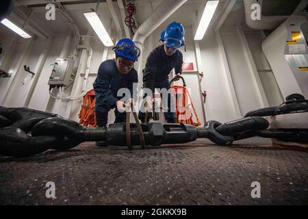 PAZIFISCHER OZEAN (20. Mai 2021) – US-Navy Seaman Ryan Deyoe, rechts, und Boatswains Mate Seaman Kim Huynh lösen eine Drehschnalle an Bord des amphibischen Angriffsschiffs USS Makin Island (LHD 8). Die Makin Island Amphibious Ready Group und die 15. Marine Expeditionary Unit führen Routineoperationen im Einsatzgebiet der 3. US-Flotte durch. Stockfoto