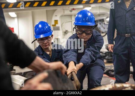 PAZIFISCHER OZEAN (20. Mai 2021) – Seeleute der US-Marine sichern sich an Bord des amphibischen Angriffsschiffs USS Makin Island (LHD 8) eine Ankerkette. Die Makin Island Amphibious Ready Group und die 15. Marine Expeditionary Unit führen Routineoperationen im Einsatzgebiet der 3. US-Flotte durch. Stockfoto