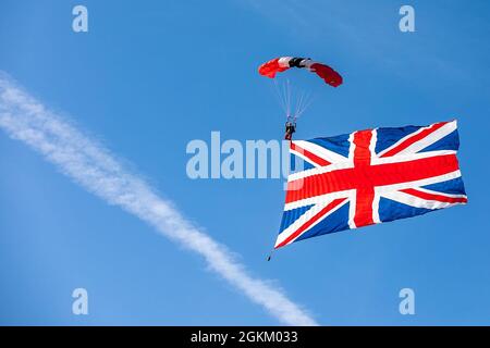 Ein Mitglied der britischen Armee Red Devils macht einen Sprung mit dem britischen Flaggen-Banner auf dem Laurinburg-Maxton Airport. Stockfoto