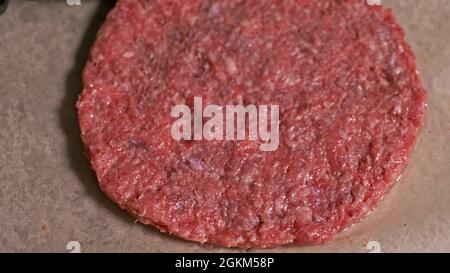 Kochen macht Fleisch Medaillons für Burger. Koch in schwarz Handschuhe macht Schnitzel essen. Die koteletts sind in Stahl Ring in eine noch Medaillon eingeebnet. Stockfoto