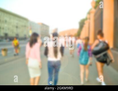 Die Menge der verschwommenen jungen Leute, die in der Stadt herumlaufen und sich unterhalten. Stockfoto