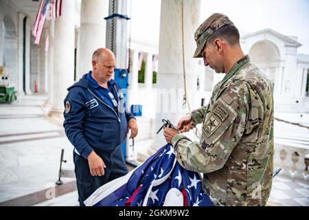 Der US-Armeekolonist Michael Binetti (rechts), Stabschef des Nationalfriedhofs von Arlington, und Dan Frye (links), Elektriker für die Instandhaltung von Anlagen, Arlington National Cemetery, helfen beim Aufhängen von US-Flaggen im Memorial Amphitheater auf dem Arlington National Cemetery, Arlington, Virginia, 25. Mai 2021. Stockfoto