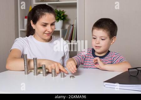 Mutter und Kind lernen finanzielle Bildung für Kinder, um zu investieren. Geld, Münzen, Einkommenswachstum und Kauf von Aktien. Stockfoto