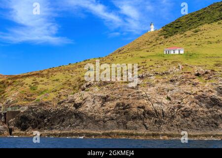 Kap Brett in der Bay of Islands, Neuseeland. Auf der rechten Seite befindet sich ein Leuchtturm und das Department of Conservation Hütte Stockfoto