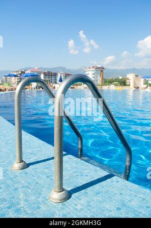 Swimmingpool mit Treppen im Hotel. Poolgeländer. Selektiver Fokus auf die Bodenfliesen. Stockfoto